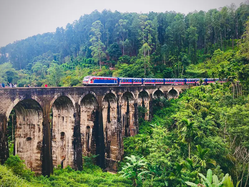 A blue train crossing the Nine Arch Bridge near Ella