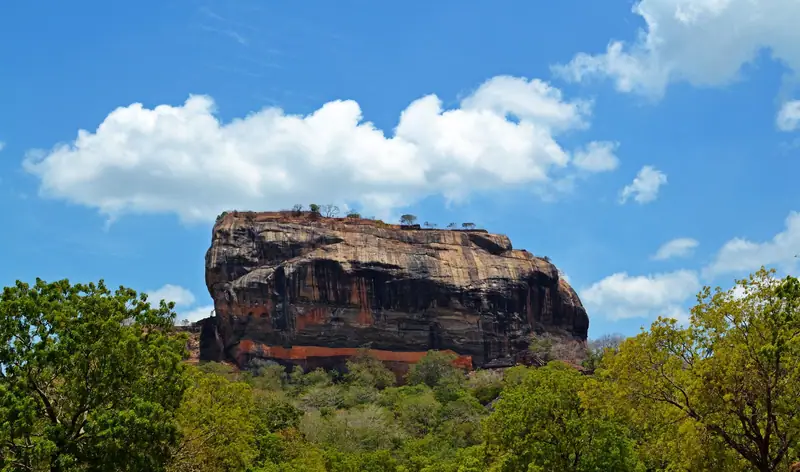 Sigiriya rock fortress rising above the forest under a blue sky